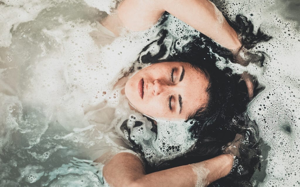 hot bath benefits, bath bombs. Girl taking a bath