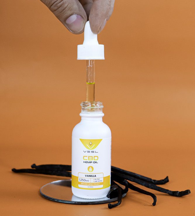 A hand holding a CBD hemp oil vanilla flavor 1250mg dropper bottle