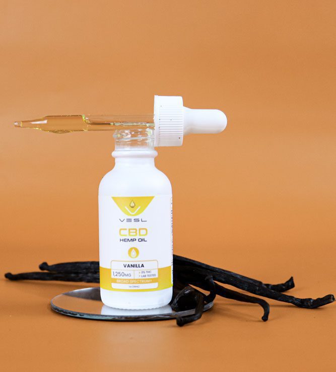 CBD hemp oil vanilla flavor on a display stand with vanilla sticks on the background